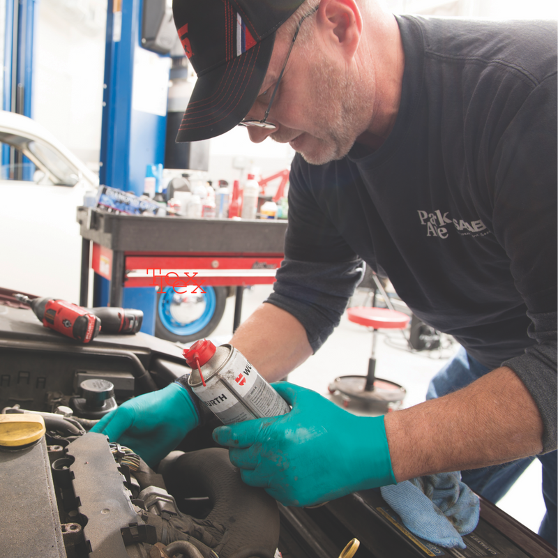 Mechanic working on a car engine with tools and equipment in the background